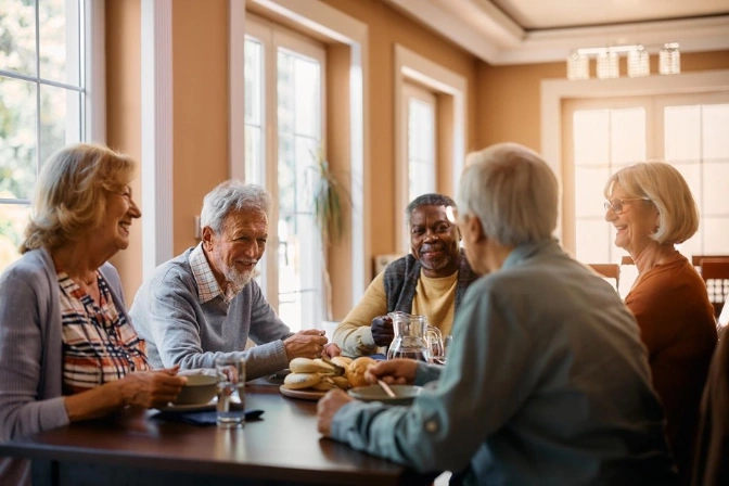 Seniors enjoying a meal and conversation in a bright, communal dining space